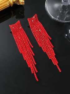 Close-up of sparkling red rhinestone fringe earrings on a black reflective surface