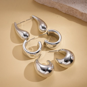 Three pairs of polished silver geometric earrings including teardrop and hoop styles