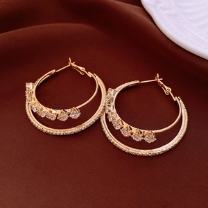 Detail view of double-layered gold earrings with paved zircons and a square crystal