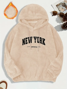 Dettaglio felpa con cappuccio beige in pile con ricamo New York e trama morbida