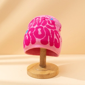 Detailed close-up of pink knitted beanie featuring groovy hot pink letter patterns