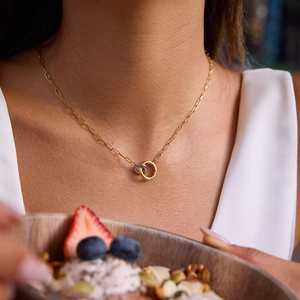 Close-up of interlocking gold and silver heart necklace on neck with paperclip chain