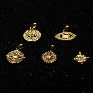 Polished 18k gold stainless steel evil eye and sunburst charms on black texture