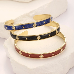 Detail of enamel star bracelets in navy, black and red on a white stone pedestal