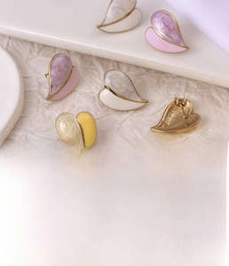 Detail of pink and white marble heart earrings in gold-plated stainless steel texture