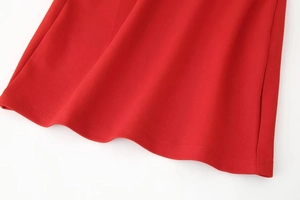 Close-up of red knitted dress hem showing fine waffle texture and double-stitch detail