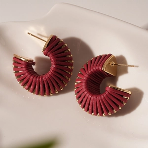 Close-up of retro burgundy faux leather thread wrapped C-shape stud earrings with gold pins
