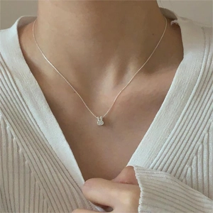 Close-up of minimalist silver rabbit pendant with crystals on a woman's collarbone