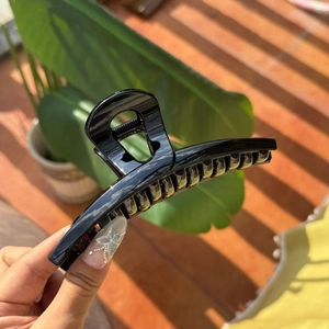 Macro shot of large hollow butterfly hair claw clip with glossy black finish texture