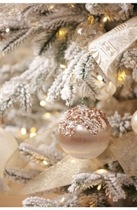 Detail of champagne gold Christmas ball with sequins and pearls on a snowy tree