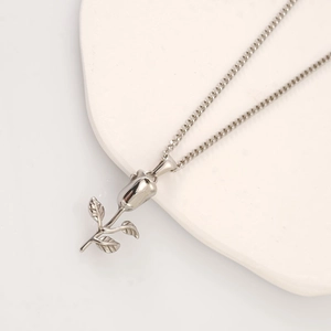 Elegant silver stainless steel rose pendant necklace on a minimalist stone display