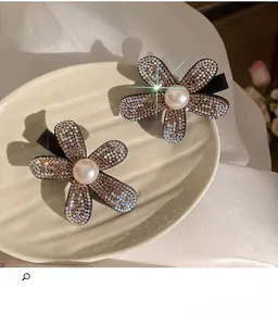 Detail of flower hair claws with full rhinestones and center pearl on beige ceramic