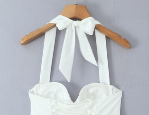 Detail eines weißen Neckholder-Tops mit Schleife am Rücken und Schnürung an der Brust