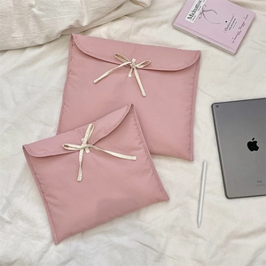 Dettaglio di custodie trapuntate rosa per laptop con fiocchi crema su lenzuola bianche
