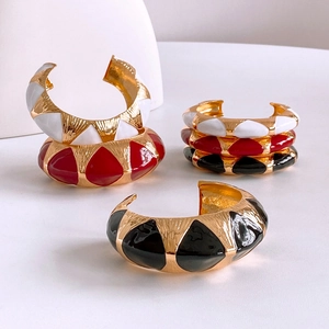 Three vintage enamel metal open bangles in gold, white, red, and black finish