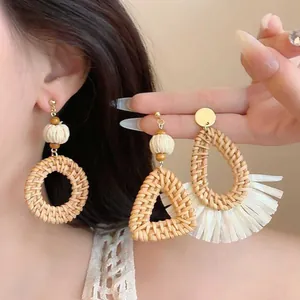 Detail of woven raffia earrings in geometric shapes with white tassel accents