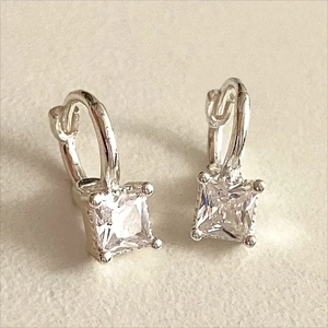 Macro detail of silver hoops with square-cut clear cubic zirconia on textured surface