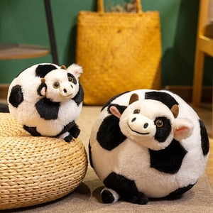 Cute round black and white plush cow toy in two sizes on a natural woven rug background