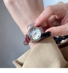 Macro detail of luxury women's quartz watch with red leather strap and crystal bezel