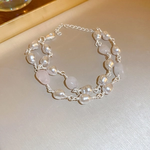 Detail of freshwater pearl and pink crystal layered bracelet on a golden tray