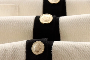 Detail of elegant gold crest buttons on a beige and black contrast knit cardigan