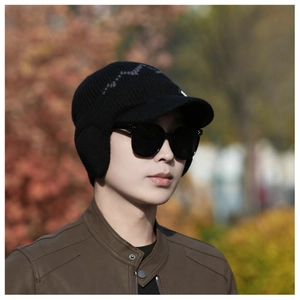 Close-up of men's winter knit hat with ear flaps and brim in a scenic outdoor setting