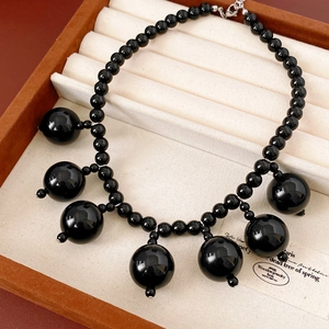 Detail view of black acrylic beaded tassel necklace inside a luxury velvet jewelry box