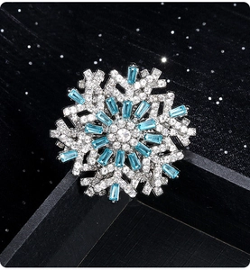 Detailed side view of 3D snowflake brooch with blue gems on black velvet base
