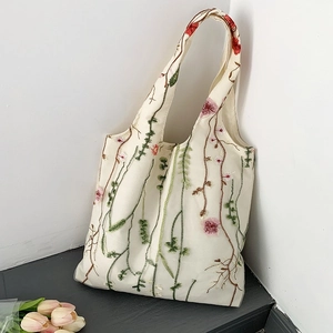 Detail of floral embroidery on off-white canvas tote bag with tulips in indoor setting