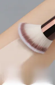 Detail of dual-ended makeup brush showing dense bristles and rose gold ferrule on skin