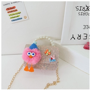 Detail of pink sequin kids purse with pearl handle, plush monster, and gold chain strap