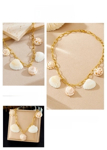 Detail view of bohemian gold chain necklace featuring white shell and conch shell pendants