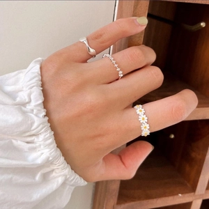 Detail of 925 sterling silver daisy ring set with polished and beaded bands on hand