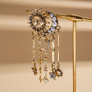 Detail of vintage gold earrings featuring celestial sun moon motifs and pearl tassels