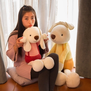Plush long-eared rabbits in pink and yellow striped clothes, warm soft home setting