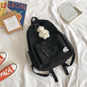 Detailed view of black canvas backpack with cute rabbit embroidery and plush bear pendant