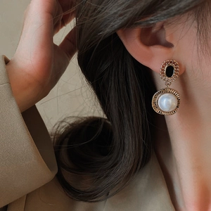 Gros plan de boucles d'oreilles vintage dorées avec gemme noire et perle de culture