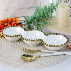 Three-compartment white ceramic dish with gold beaded edges in an elegant setting