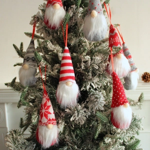 Knitted Christmas gnome ornaments in red and grey hanging on a snowy festive tree