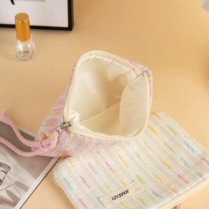 Detail of striped woven makeup bags in pink and cream with zipper and wristlet