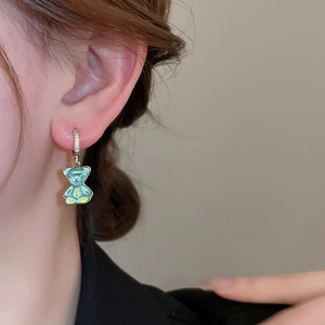 Gros plan de boucles d'oreilles ours bleu sarcelle translucide avec anneau en zircon sur modèle