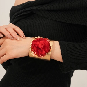 Gros plan d'une large manchette dorée ornée d'une grande fleur en tissu rouge vif