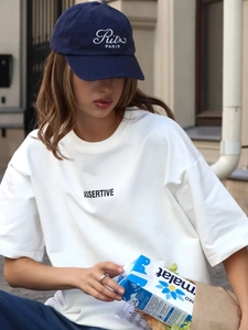Dettaglio di una t-shirt bianca in cotone con stampa e cappellino da baseball Ritz Paris