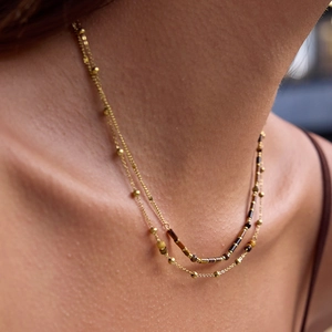 Close-up of double-layer necklace with tiger eye beads and gold spheres on a model