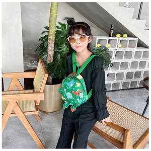 Kid-sized backpack with colorful dinosaur pattern worn by a model in a natural setting