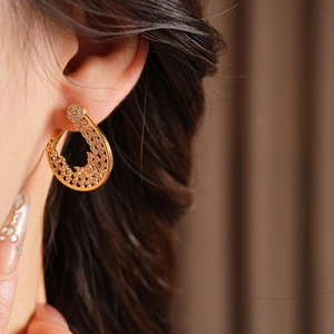 Close-up of gold-plated flower hoop earrings with pavé zircons worn by a model
