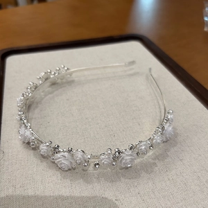 Close-up of silver headband with delicate white resin flowers and faux pearls detail