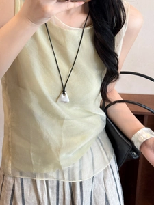 Minimalist necklace with white geometric pendant on a black cord worn by a model