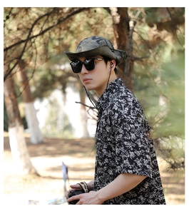 Outdoor look featuring a camouflage sun hat, floral shirt, and sunglasses for travel