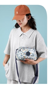 Detail of floral nylon crossbody bag featuring multiple zipper compartments and adjustable strap